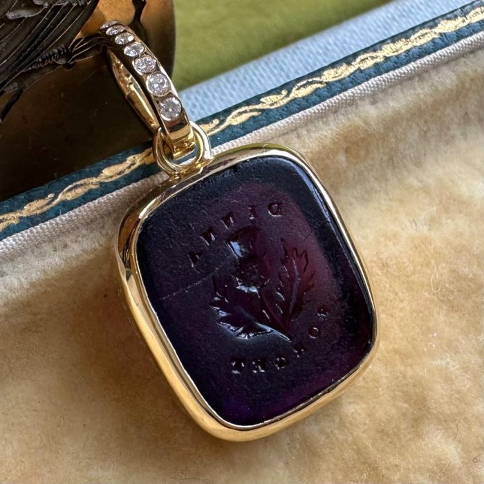 Intaglio gold pendant with purple paste seal featuring a seal with the words Dinna Forget