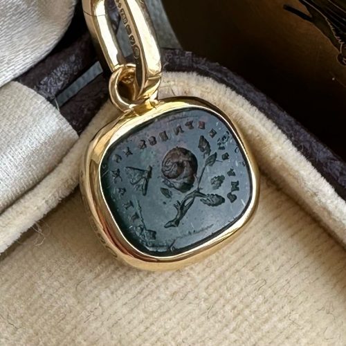 Close up of bloodstone paste pendant featuring rose and butterfly intaglio