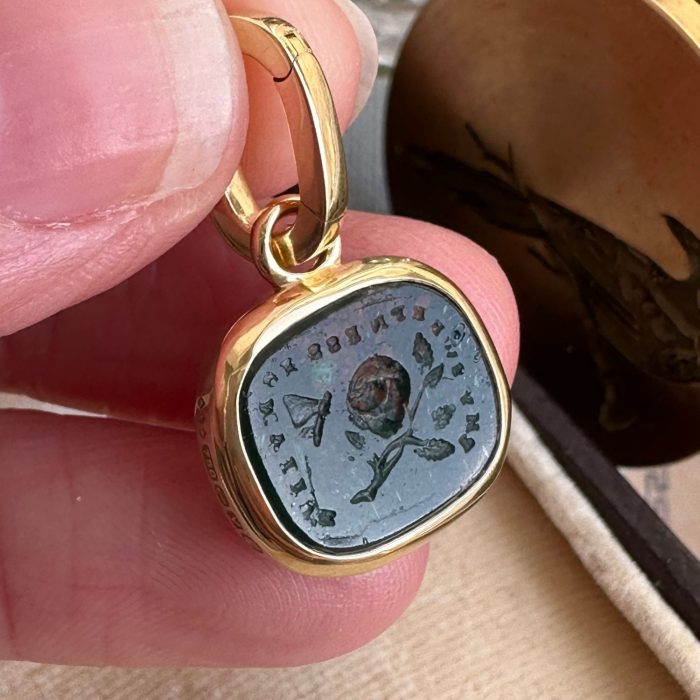 Close up of bloodstone paste pendant featuring rose and butterfly intaglio