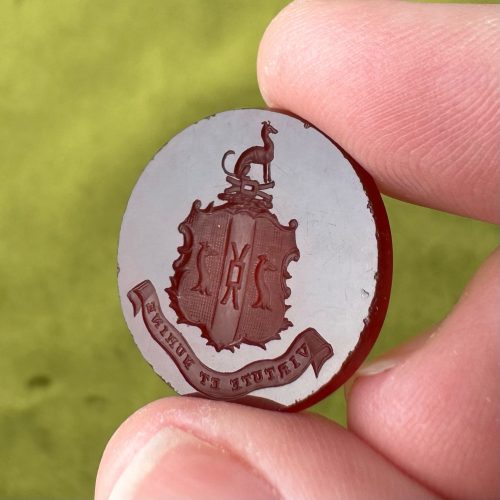 Deep red, circular carnelian intaglio, imagery of an ornate armorial with three greyhounds and Latin text virtute et numine, with virtue and divine will