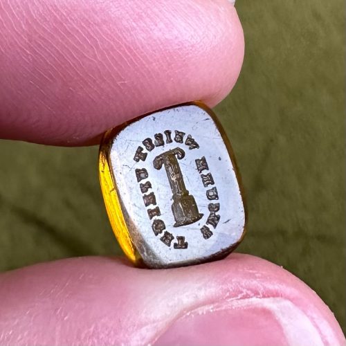 Yellow paste intaglio seal featuring a Doric column surrounded by the inscription Secure Whilst Upright