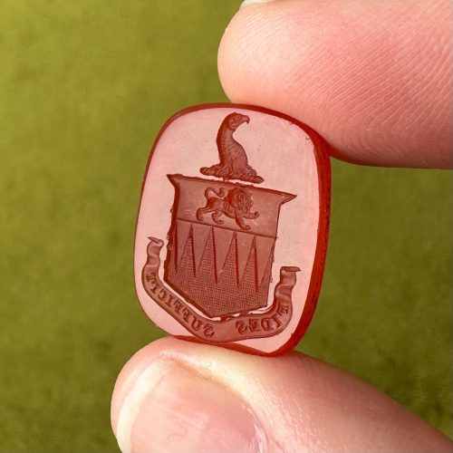 Large Georgian rounded rectangle carnelian intaglio seal with imagery of a shield containing a lion passant, topped with a crest depicting an eagle’s head in profile. Latin text fides sufficit, faith is sufficient, in a banner at the bottom