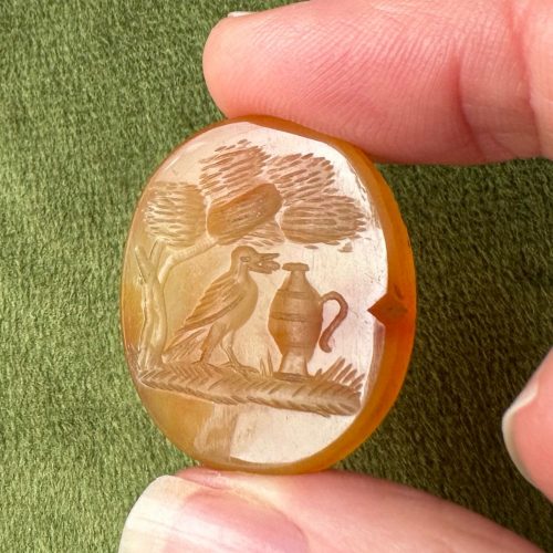 Impressively large oval carnelian intaglio with imagery of a crow (with a pebble in its beak) and a pitcher, under the shade of a tree