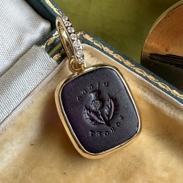 Intaglio gold pendant with purple paste seal featuring a seal with the words Dinna Forget