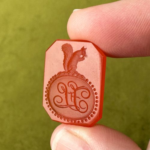 Elongated octagon intaglio seal with delightfully detailed imagery of a squirrel holding a nut atop initials FL in ornate script