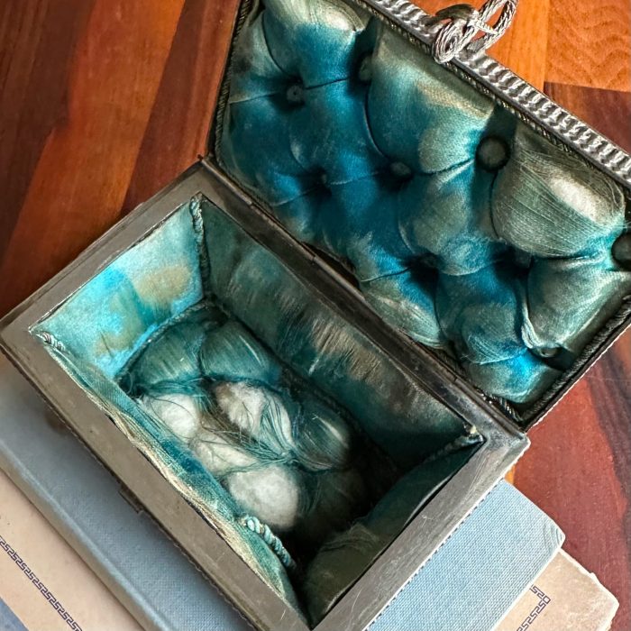 Inside of alabaster trinket box showing worn blue silk lining