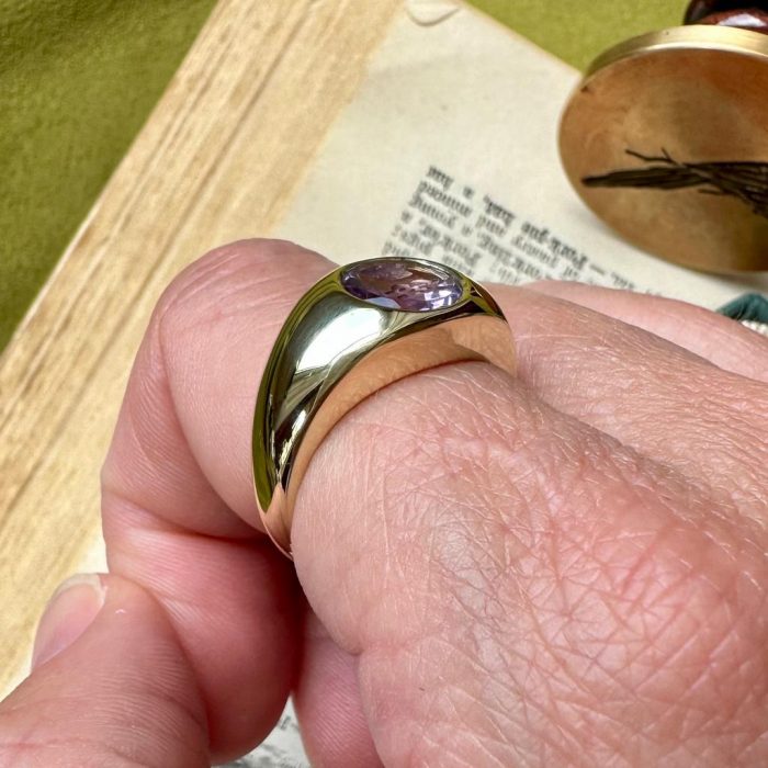 Close up of rubover intaglio seal ring on finger showing setting