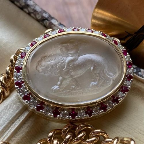 Close up of intaglio featuring Cupid riding Aslan with ruby and diamond bezel and integrated chain